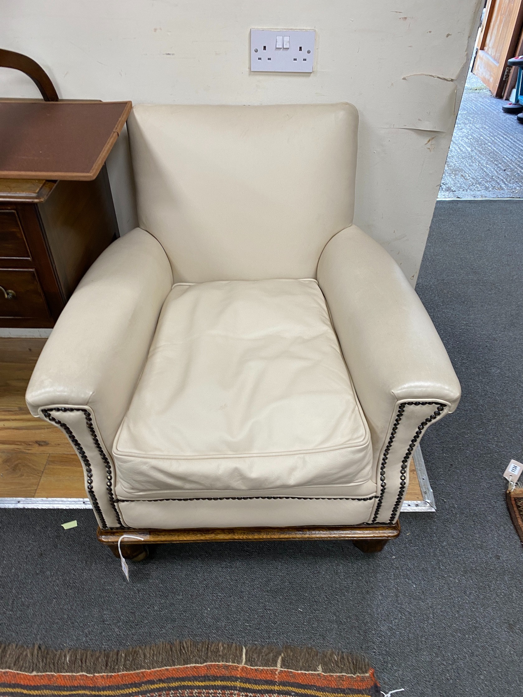 A pair of early 20th century oak cream leather club armchairs, width 76cm, depth 79cm, height 78cm